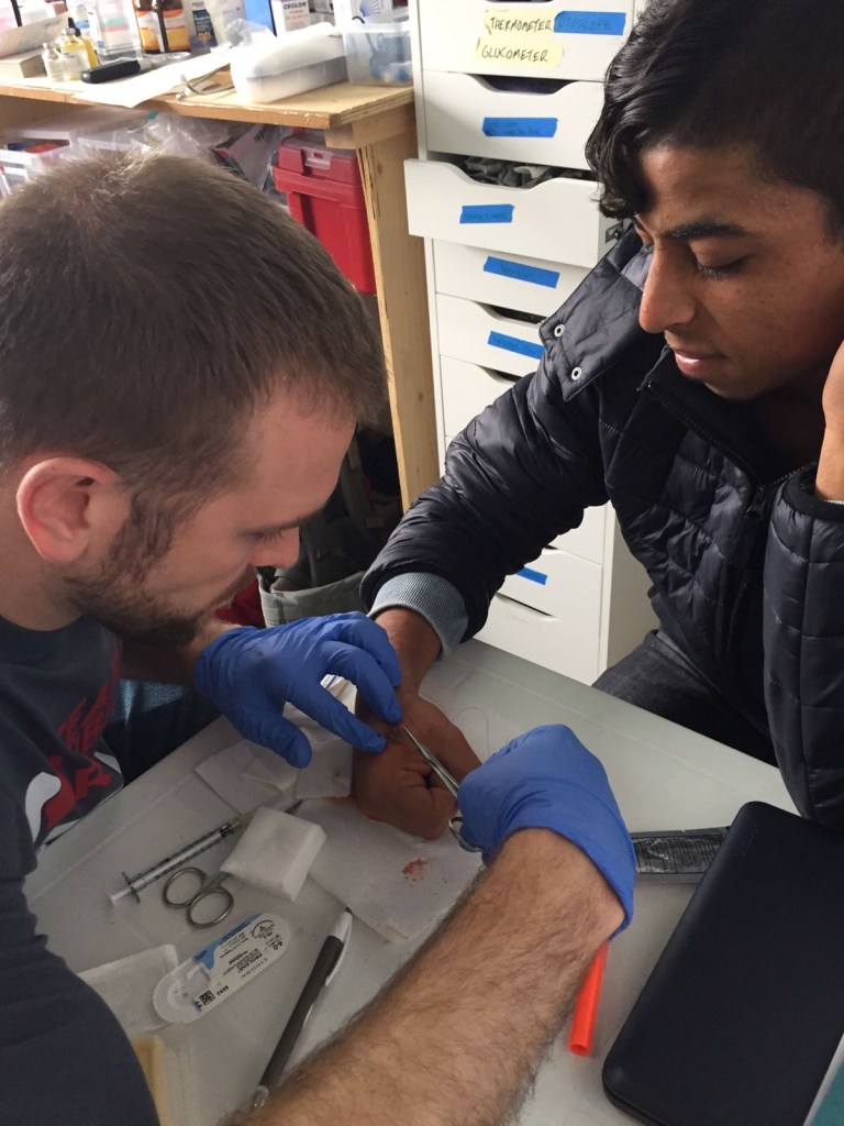 Pediatrician suturing a hand injury at the refugee camp clinic